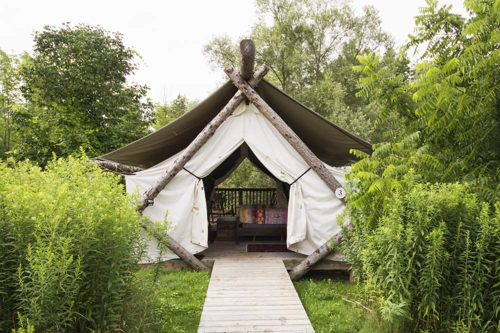 Glamping tent with tree beams and white canvas sheets as cover