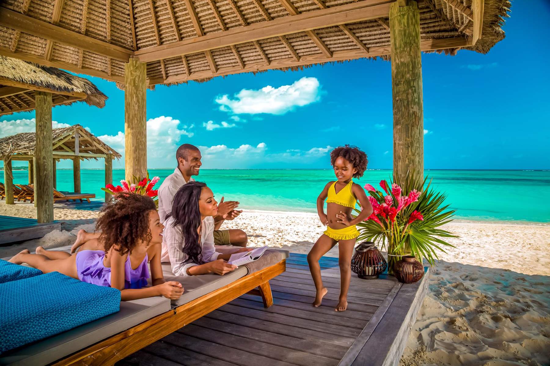  A family of four is relaxing in a luxury beach hut on a tropical beach.